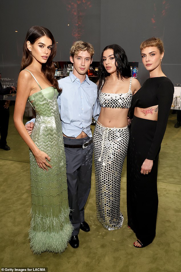 Earlier in the evening, Charli stunned in a dazzling silver crop top and skirt as she posed with LR Kaia Gerber, Troye Sivan and Cara Delevingne