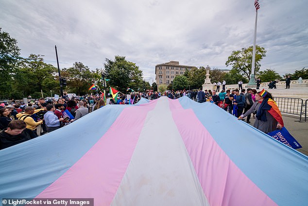 A giant trans flag is unfurled outside the Supreme Court during the Court's earlier hearing in a case over LGBTQ rights. The Biden administration asked the court to take up the new case after a lower court upheld a ban on surgeries and treatments in Tennessee