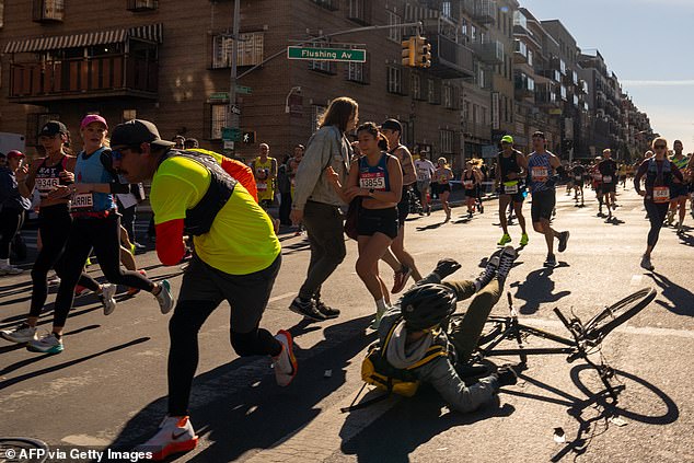 A cyclist is knocked to the ground by passing runners during the 2024 New York Marathon