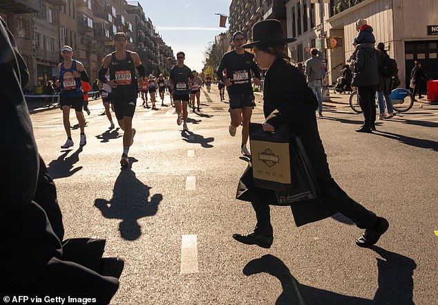 A child runs across the street as marathon runners from New York make their way around the course