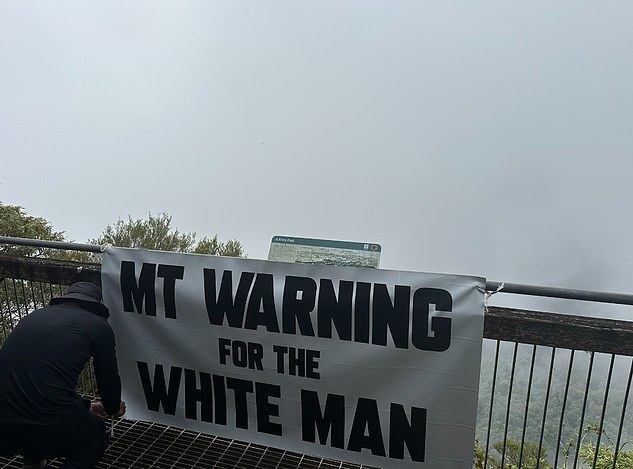 A member of the black-clad and masked group was seen tying the sign to the lookout fence