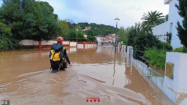 An aid worker wades through the water in Catalonia this morning