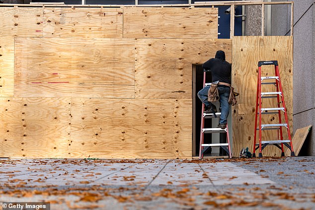 Workers are seen boarding up storefronts and ground-floor buildings along Pennsylvania Avenue near the White House