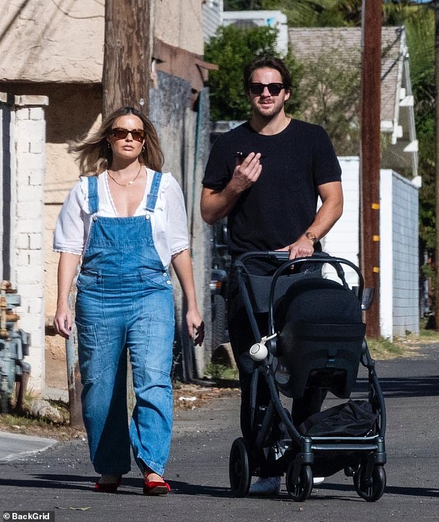 Her husband walked beside her as he proudly pushed a stylish black stroller with their little one