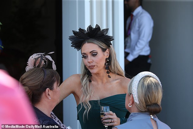 Her blonde hair was styled straight and sleek, with a statement oversized black fascinator topping off her look – a classic touch of race day flair