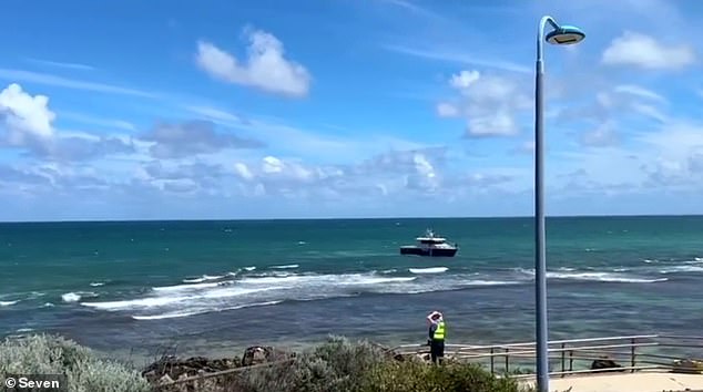 WA Police confirmed in a statement that the woman was a female officer, who was off duty at the time (photo Water Police and a police officer at Trigg Beach in Perth on Tuesday)