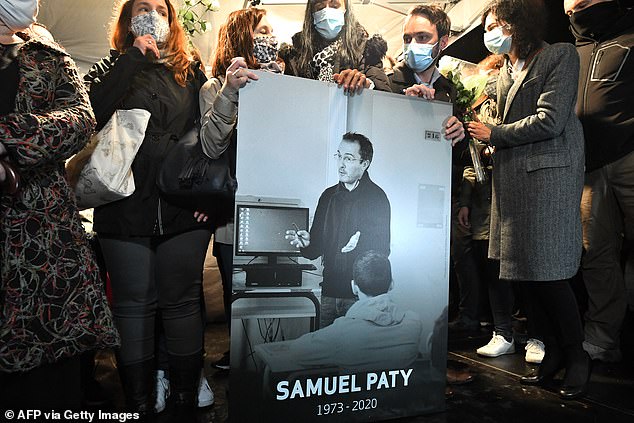 Family members and colleagues hold a photo of Samuel Paty