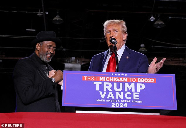 Republican presidential candidate and former US President Donald Trump speaks on stage next to former boxer Thomas "Touch man" Hearns, during a rally at Huntington Place in Detroit, Michigan, U.S. on October 18, 2024. Trump saw pre-election margins improve among Black and Hispanic voters compared to his 2020 numbers