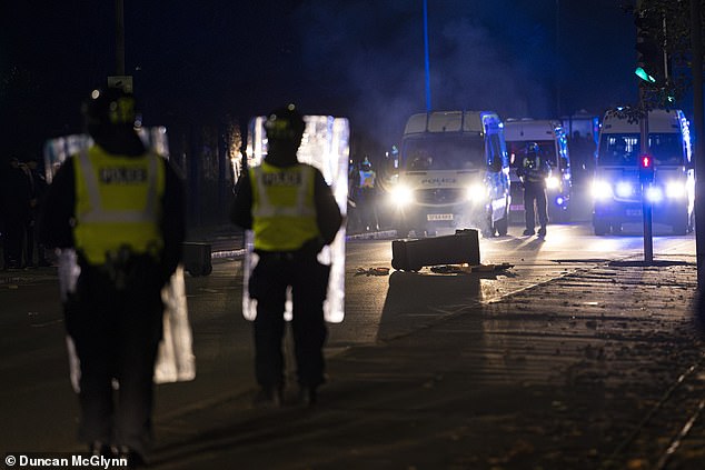 Riot police in Niddrie, Edinburgh, Scotland, as fireworks, rocks and glass bottles are thrown at them after disturbances begin in the area of ​​the Scottish capital