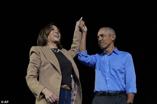 Barack Obama holds up Harris' hand during a joint campaign rally at James R. Hallford Stadium in Clarkston, Georgia on October 24