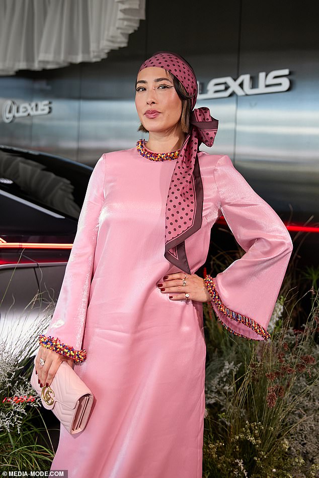 The former MasterChef judge, 42, put on a daring show in a bright pink satin dress with colorful rainbow beaded cuffs as she posed in the Lexus tent