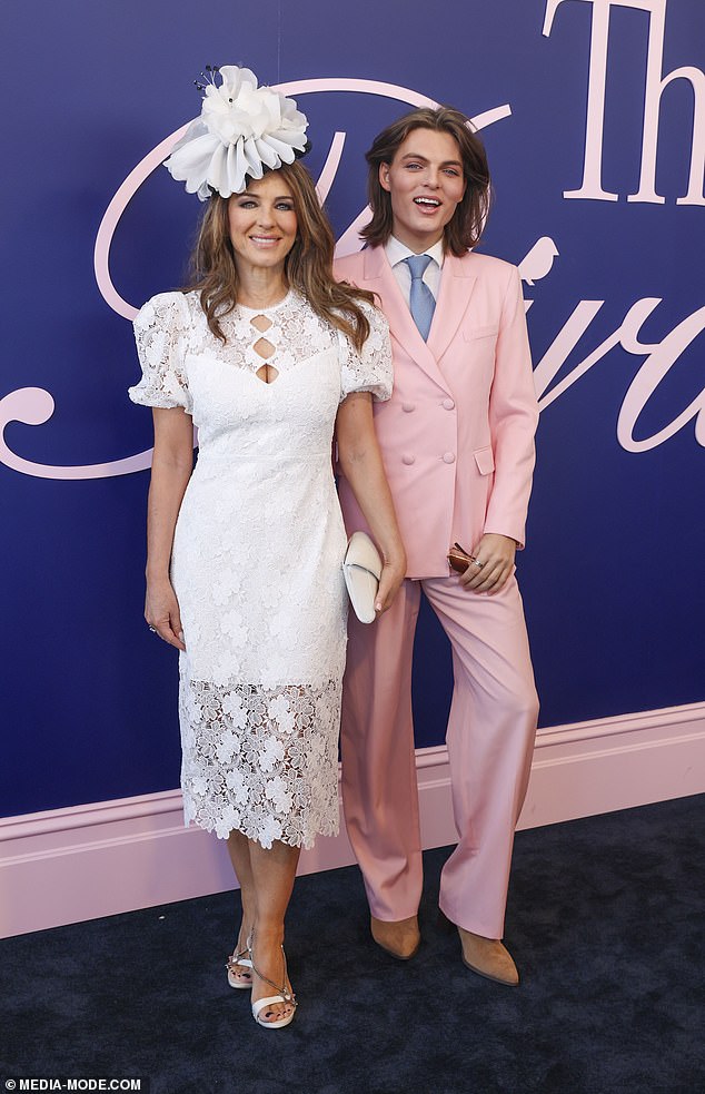 She added a few extra inches to her frame in a pair of white heeled sandals and packed her essentials into a cream handbag. (Pictured with son Damian)