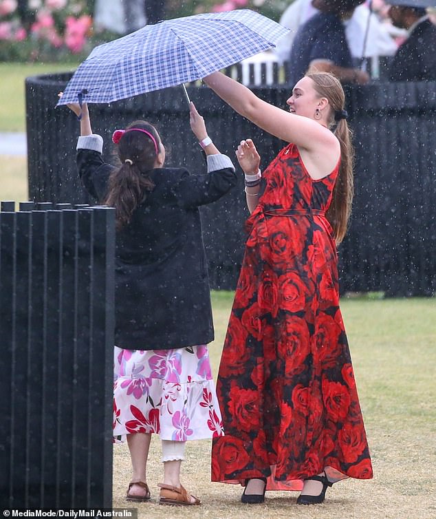 Racegoers crowded under umbrellas as showers hit Flemington on Thursday