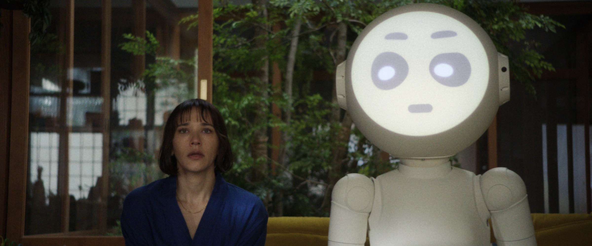 Robot Sunny looks askance at Suzie (Rashida Jones) standing next to her in a still of Sunny