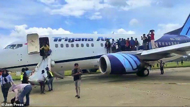 The photo shows people escaping from a plane via an emergency slide after a passenger saw smoke coming from the plane's engine