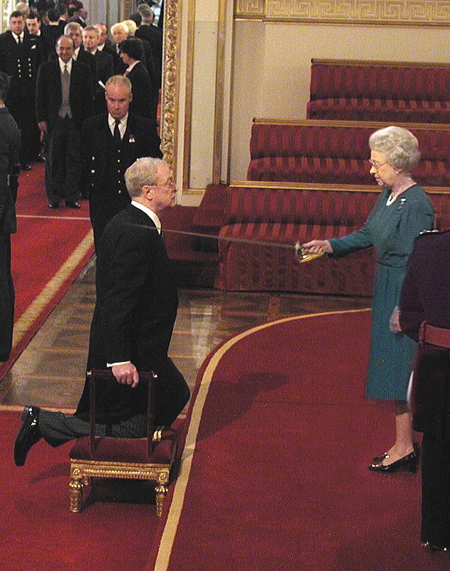 Michael Caine kneels as he is knighted by the Queen at Buckingham Palace, November 2000