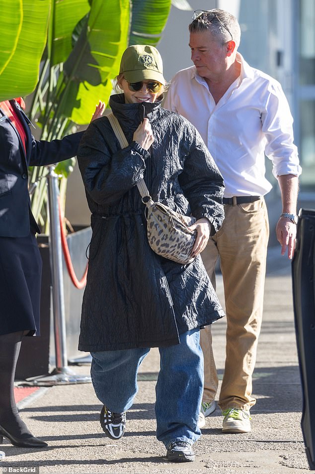 The Australian pop legend, 58, wore a large black overcoat over a baggy T-shirt, teaming it with casual jeans and black sneakers