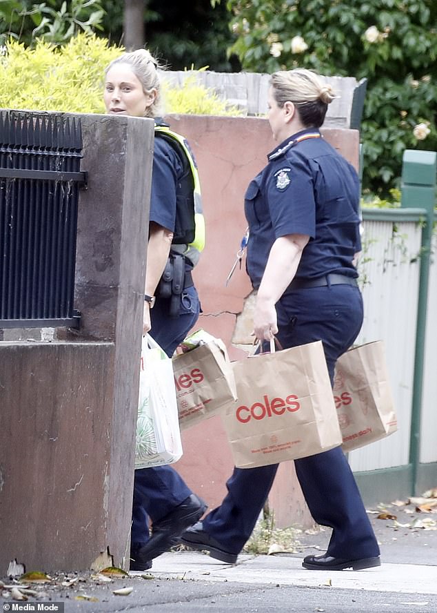 Busted: A Victoria police officer sees a Daily Mail Australia photographer documenting her grocery delivery