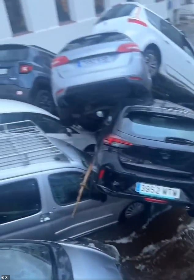 Another video shows several cars piled up near a bridge elsewhere in the Spanish city, recently destroyed by floods.