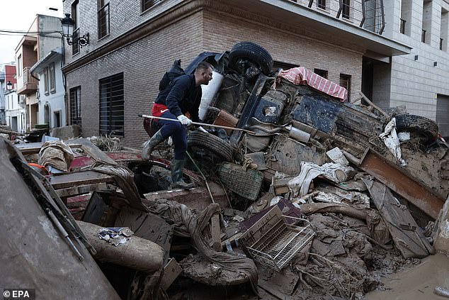 A man walks over rubble to access a mud-covered street in the flood-hit town of Paiporta, Valencia, Spain, November 7, 2024