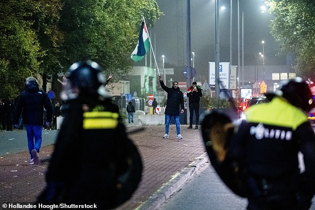 A demonstrator with a Palestinian flag and Mobile Unit (ME) during a pro-Palestinian demonstration during Ajax - Maccabi Tel-Aviv on Anton de Komplein