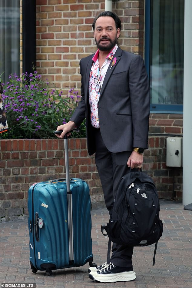 He paired the trendy shirt with a smart dark gray blazer and matching trousers as he waited patiently with his things