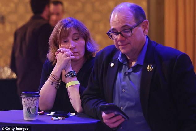 People check election results on their phones while attending an election night watch party for Senator Bob Casey