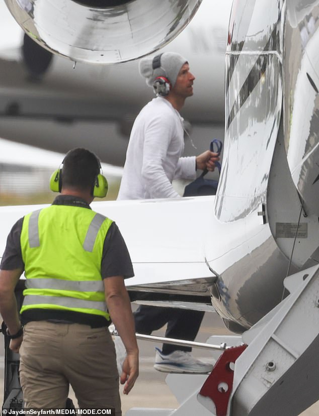 Chris is pictured boarding the plane after kissing the tarmac