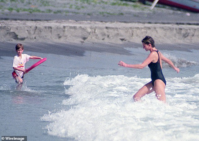 The late Princess of Wales wades through the waves towards Harry, who is holding a board