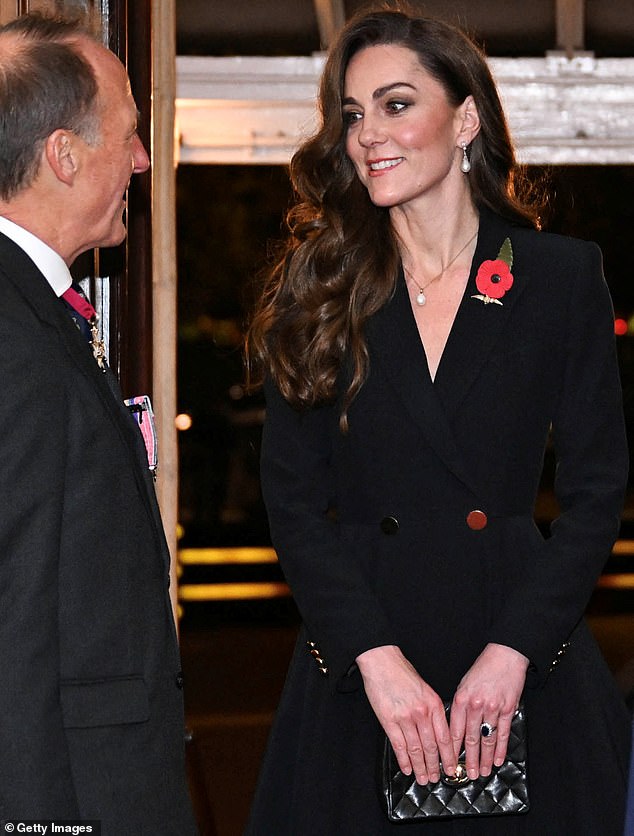 Always on trend, Kate wore a midi black dress with a deep V-neck collar to suit her slim figure, accessorized with a stylish black clutch.