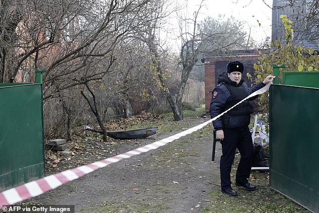 A Russian police officer pulls off warning tape at the site of a drone attack in the village of Stanovoye, Moscow region, on November 10