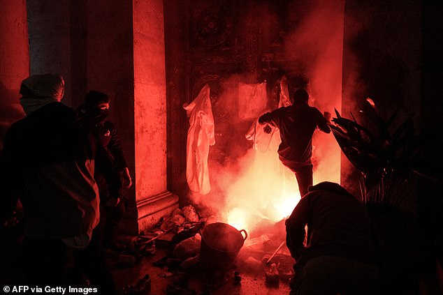 Protesters kick the entrance to the City Hall as a flare is lit during a demonstration to demand the resignation of Valencia Regional President Carlos Mazon in Valencia on November 9, 2024