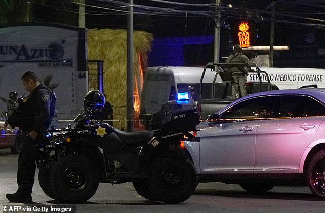 A Mexican army soldier and a public security officer stand guard outside the bar in Los Cantaritos