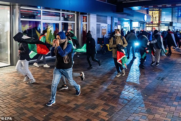 Protesters run with Palestinian flags ahead of the UEFA Europa League match between Ajax and Maccabi Tel Aviv at Anton de Komplein in Amsterdam, Netherlands, November 7, 2024.