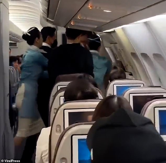 Several flight attendants try to grab the man after seeing him go to the door