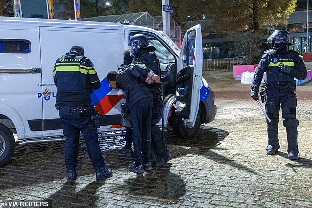 Dutch police officers arrest a man after riots in Amsterdam as violence continues in the city