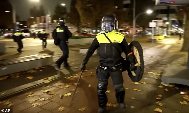 Police officers in riot gear patrol the streets of Amsterdam after more violence