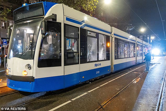 A man stands next to the tram, the windows of which were smashed during the riots