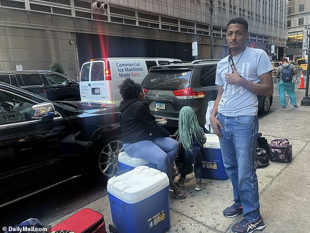 Asylum seeker Fernando Peralta, 34, sells drinks from a cooler outside the Roosevelt Hotel