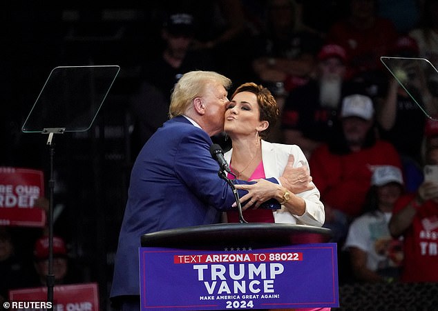 Trump and Lake embrace and share a cheek kiss while campaigning together at a rally in Prescott Valley, Arizona on October 13, 2024