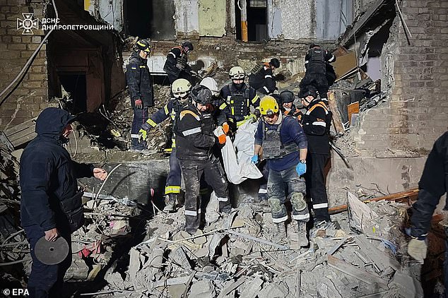 A handout photo made available by the State Emergency Service of Ukraine on November 12, 2024 shows Ukrainian rescuers carrying the body of a woman at the site of a slide bomb attack on a residential building in Zaporizhia, Ukraine, November 11, 2024