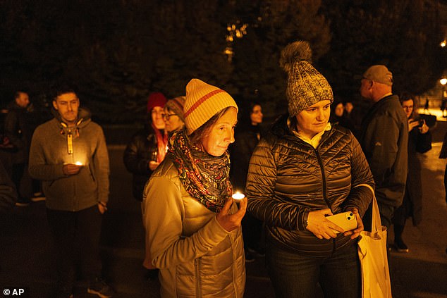 Friends hold candles as they remember Michalski during a candlelight vigil in Budapest, Hungary, Saturday, November 9