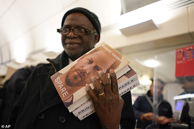 A customer holds copies of 'Spare' in a London bookstore during a midnight opening in 2023