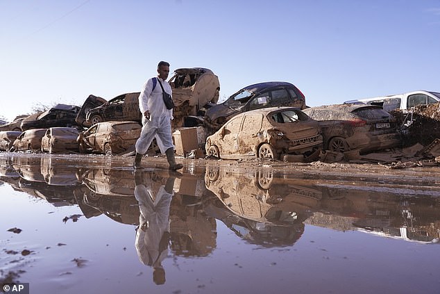 A man walks past piled-up cars after floods in Catarroja left hundreds dead or missing in Spain's Valencia region, Tuesday, November 12, 2024