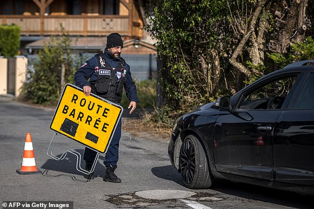 A supervisor closes the road to the hamlet above Taninges, French Alps, where three children were found dead the day before, November 13, 2024