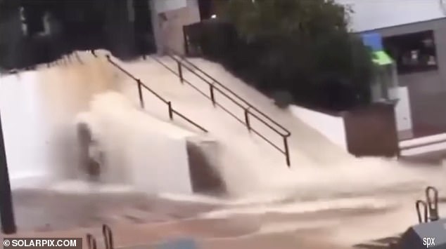 Residents watched as streams of water poured down a staircase within meters of shops and homes