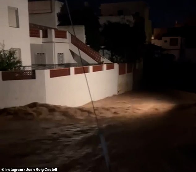 Floodwaters flow past houses in southeastern Spain