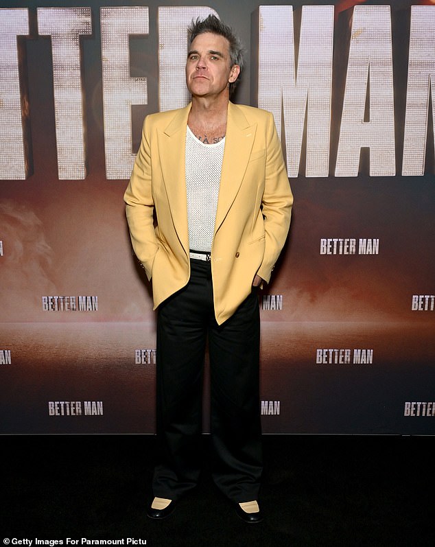 Robbie Williams turned heads in a yellow blazer as he posed on the red carpet for his biopic Better Man screening in New York City on Wednesday