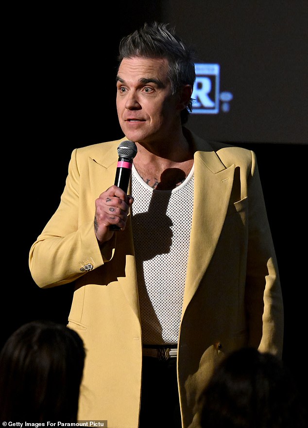 Robbie was all smiles as he added a white mesh tank top under the statement blazer as he posed on the red carpet held at the city's Metrograph