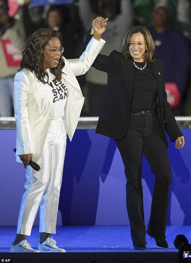 Oprah Winfrey holds hands with Kamala Harris after introducing the vice president to speak at a campaign rally outside the Philadelphia Museum of Art.